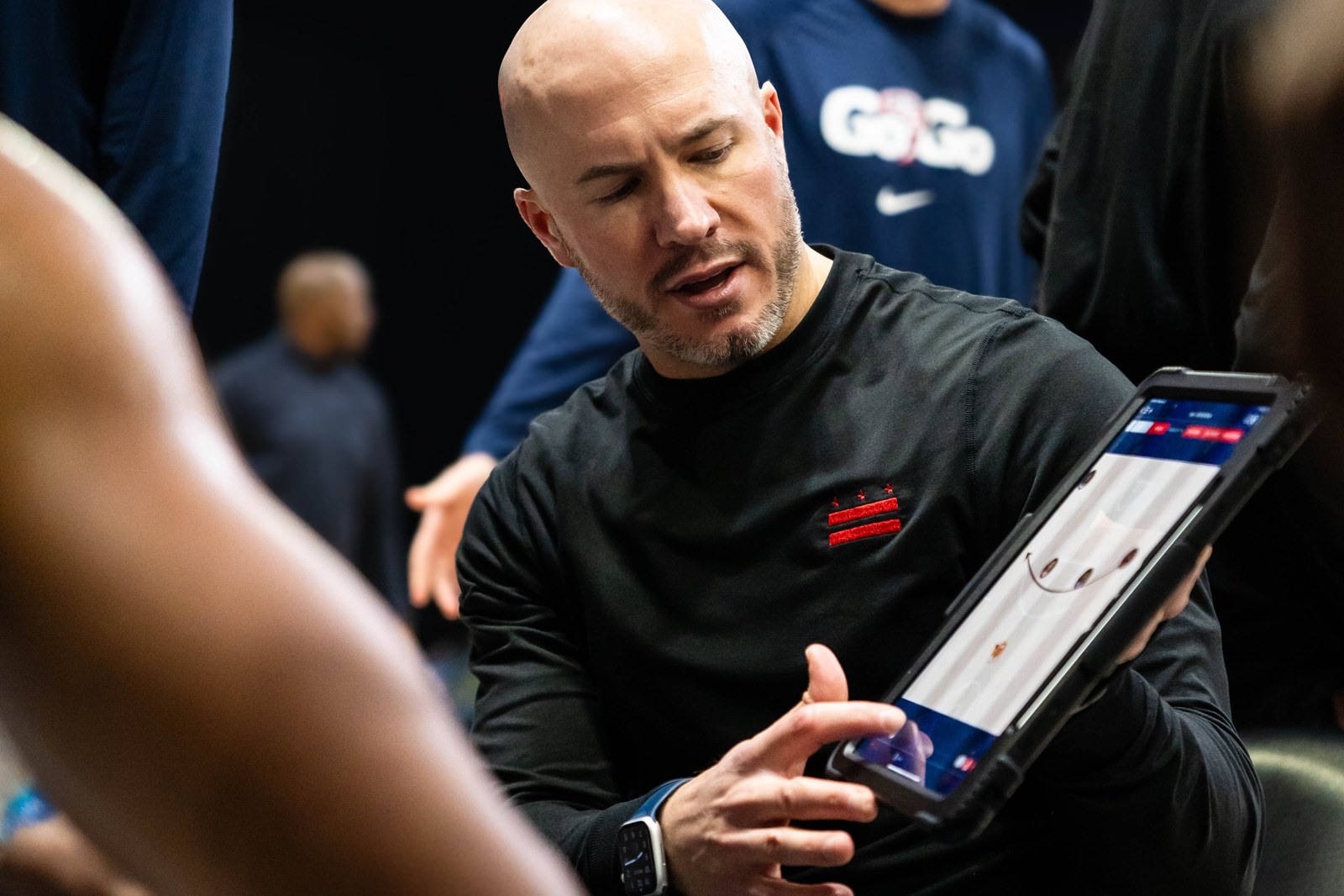 Cody Toppert holding an iPad showing an animated Luceo play during a Capital City Go-Go timeout huddle
